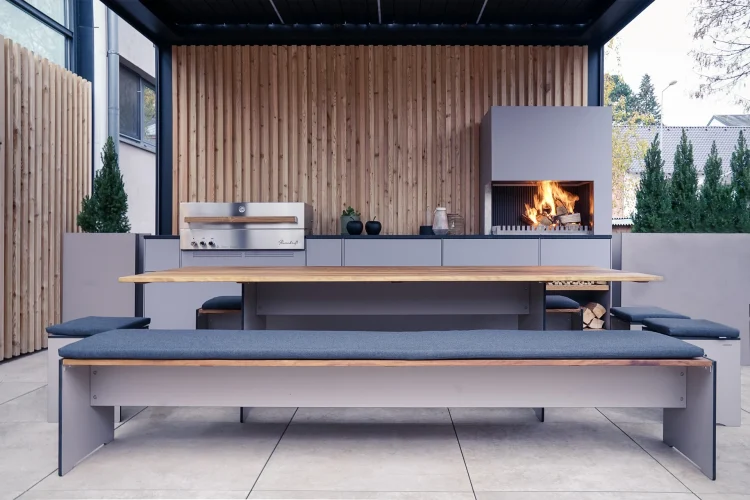 Design-Outdoor-Küche mit Kamin, Grill und gepolstertem Sitzbereich bei Tageslicht