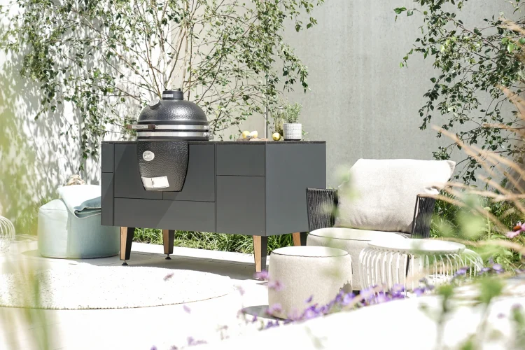 Keramikgrill in moderner Outdoor-Küche mit Lounge-Möbeln und mediterraner Bepflanzung