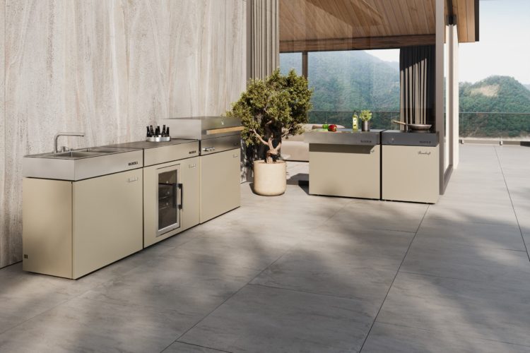 Exklusive Outdoor-Küche in hellem Beigeton mit Edelstahloberfläche und Panoramaausblick ins Gebirge