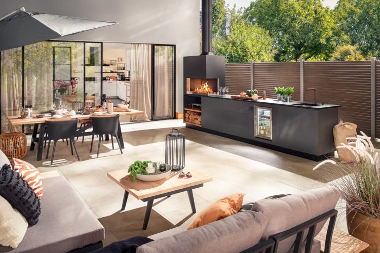 Designorientierte Outdoor-Küche mit Lounge-Bereich, Esstisch und Kamin im Gartenambiente